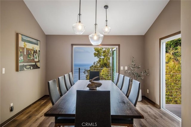 dining area featuring a water view, vaulted ceiling, and hardwood / wood-style floors