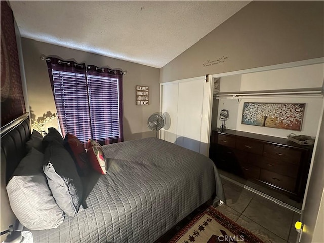 bedroom featuring a textured ceiling, tile patterned flooring, and lofted ceiling