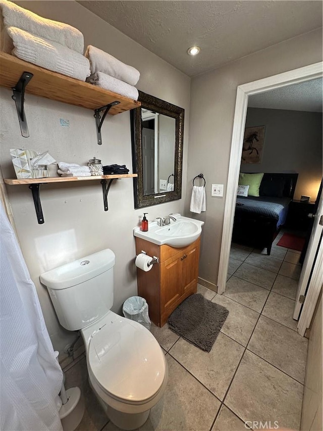 bathroom featuring toilet, vanity, tile patterned flooring, and a textured ceiling