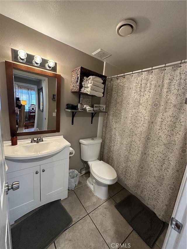 bathroom with a textured ceiling, tile patterned floors, vanity, and toilet