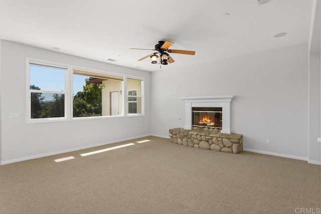 unfurnished living room with ceiling fan, carpet, and a fireplace