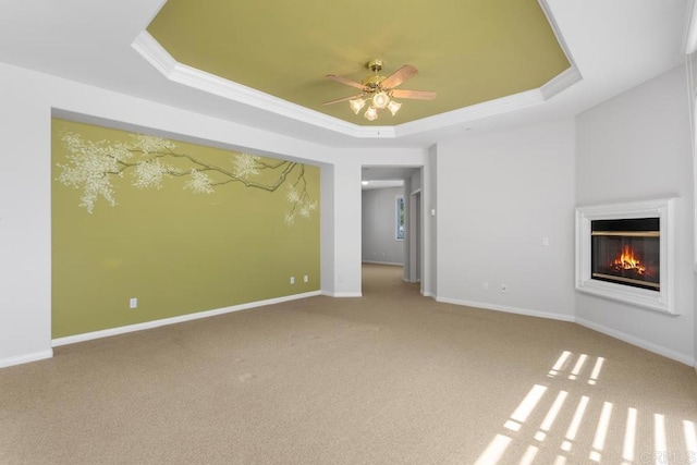 unfurnished living room featuring ceiling fan, a tray ceiling, and carpet flooring