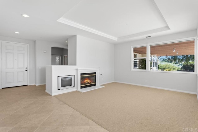 unfurnished living room with light tile patterned floors, ornamental molding, and a raised ceiling