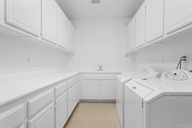 laundry room featuring cabinets, light tile patterned floors, and separate washer and dryer