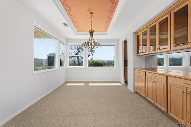 unfurnished dining area with light carpet, an inviting chandelier, plenty of natural light, and a raised ceiling