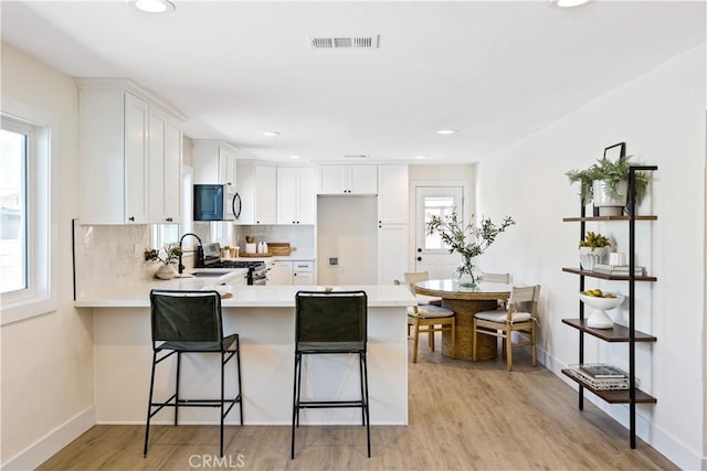 kitchen featuring white cabinets, kitchen peninsula, stainless steel appliances, and a kitchen bar