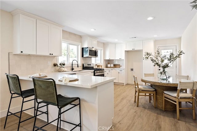 kitchen featuring light wood-type flooring, a breakfast bar area, appliances with stainless steel finishes, and white cabinetry