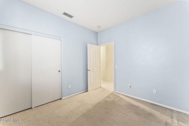 unfurnished bedroom with light colored carpet and a closet