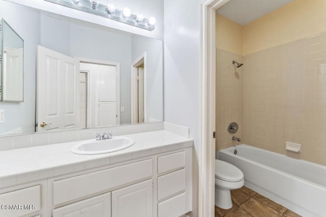 full bathroom with toilet, tiled shower / bath combo, and vanity