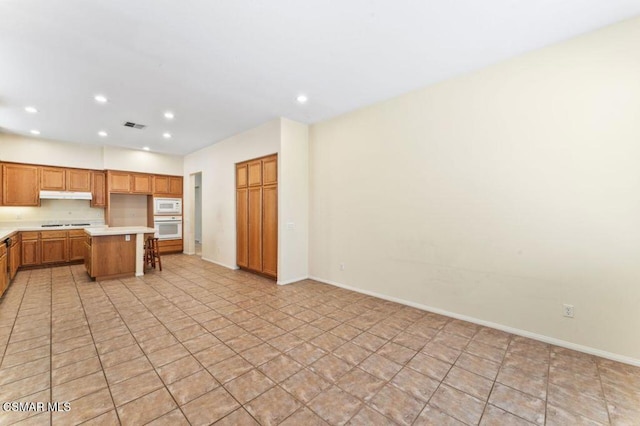 kitchen with a kitchen bar, a center island, and white appliances