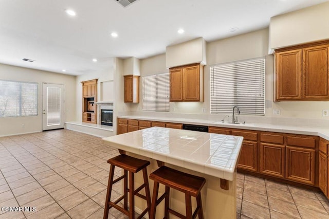 kitchen with tile countertops, a center island, sink, a breakfast bar area, and light tile patterned floors