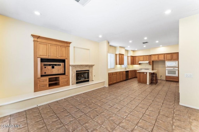 kitchen featuring white appliances, a center island, a premium fireplace, sink, and a breakfast bar