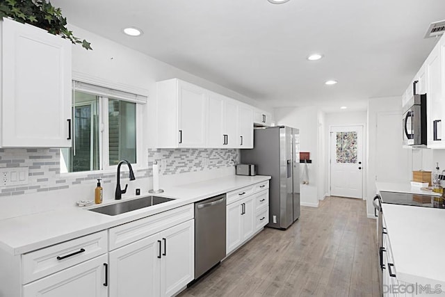 kitchen featuring light wood-type flooring, stainless steel appliances, white cabinetry, and sink