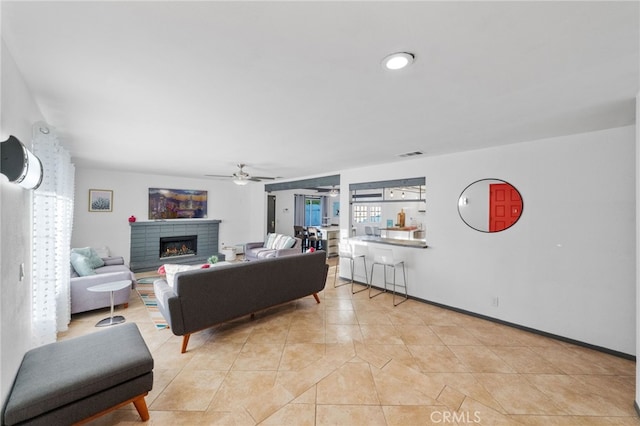 living room with ceiling fan, light tile patterned flooring, and a fireplace