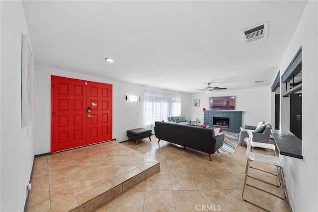 living room featuring a brick fireplace, light tile patterned floors, and ceiling fan