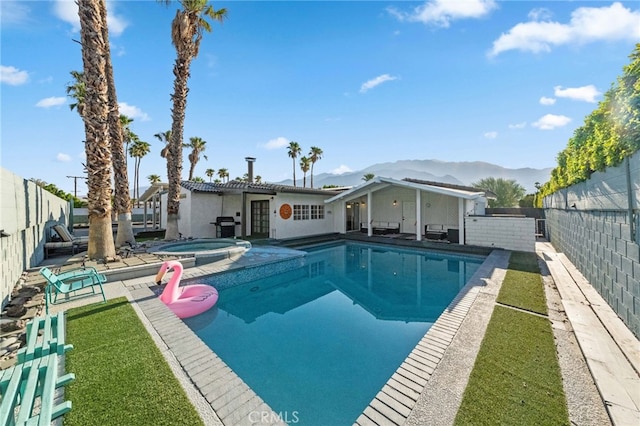 view of swimming pool with a patio area, a mountain view, and an in ground hot tub