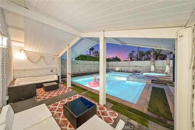 pool at dusk featuring an outdoor living space, a patio area, and an in ground hot tub