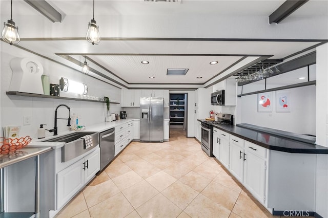 kitchen with appliances with stainless steel finishes, white cabinetry, and pendant lighting