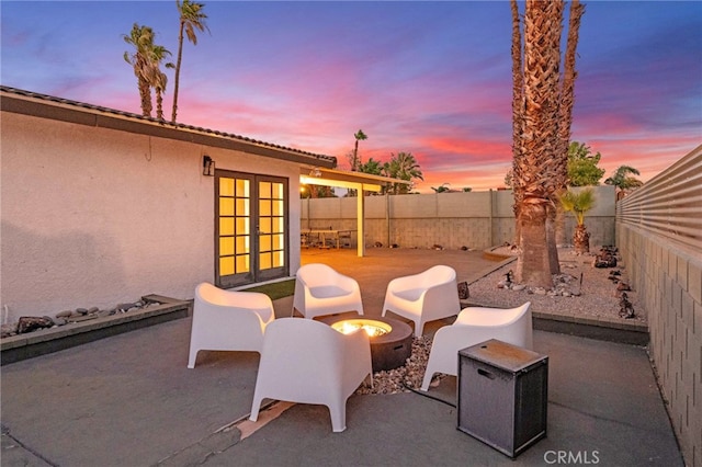 patio terrace at dusk featuring an outdoor fire pit and french doors