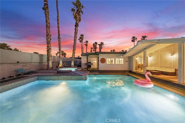 pool at dusk with an in ground hot tub and an outdoor living space