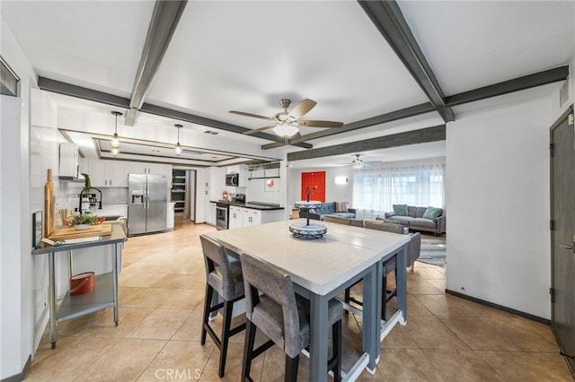 kitchen featuring appliances with stainless steel finishes, light tile patterned flooring, pendant lighting, white cabinets, and sink