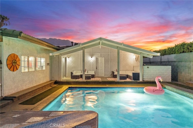 pool at dusk featuring outdoor lounge area