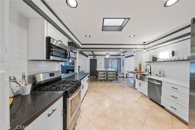 kitchen featuring tasteful backsplash, ceiling fan, sink, white cabinetry, and appliances with stainless steel finishes