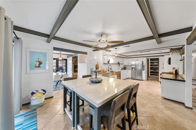 dining room with ceiling fan, light tile patterned floors, beam ceiling, and sink