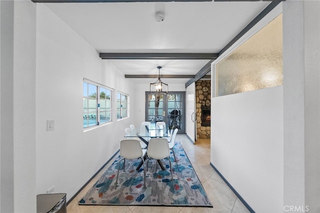 dining space featuring beamed ceiling, a stone fireplace, and light tile patterned flooring