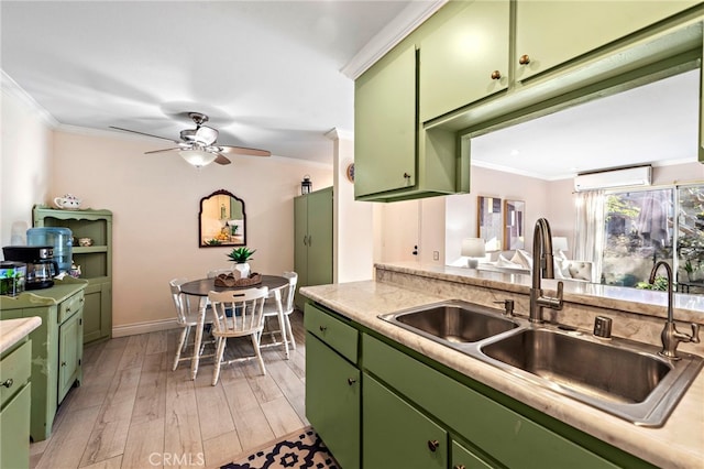 kitchen featuring sink, ornamental molding, light wood-type flooring, ceiling fan, and green cabinets