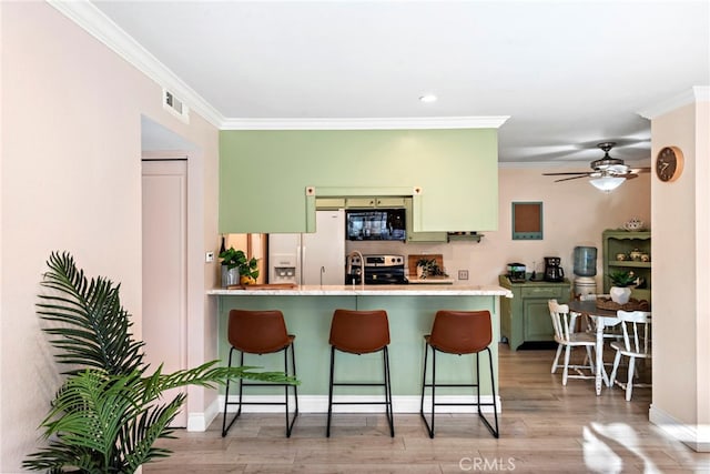 kitchen featuring kitchen peninsula, white fridge with ice dispenser, green cabinetry, ornamental molding, and a breakfast bar