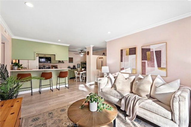 living room featuring ceiling fan, crown molding, and light hardwood / wood-style floors