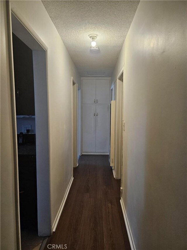 corridor with dark hardwood / wood-style floors and a textured ceiling