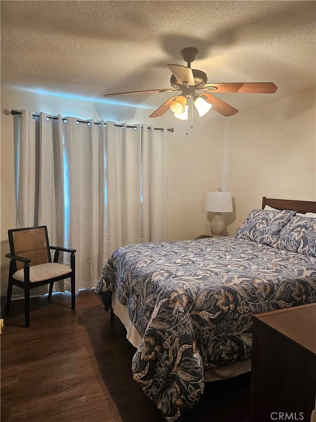 bedroom with ceiling fan, dark wood-type flooring, and a textured ceiling