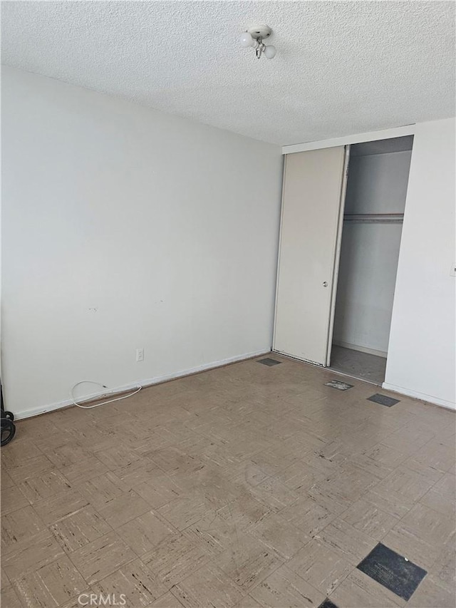 unfurnished bedroom featuring a textured ceiling and a closet