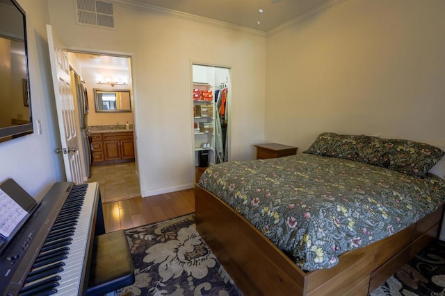 bedroom featuring ensuite bathroom, hardwood / wood-style floors, crown molding, a walk in closet, and a closet