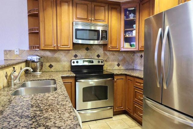 kitchen featuring backsplash, light stone countertops, sink, and stainless steel appliances