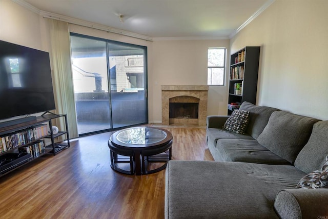 living room featuring hardwood / wood-style flooring, crown molding, and a tiled fireplace