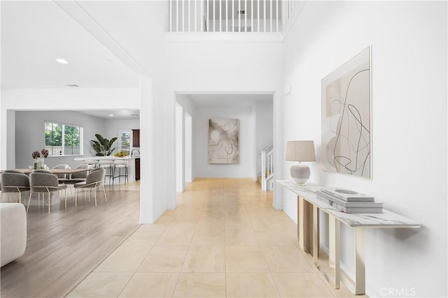 hallway featuring light tile patterned floors and a towering ceiling