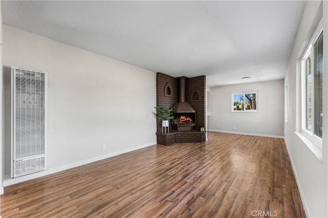 unfurnished living room featuring a wood stove and hardwood / wood-style floors