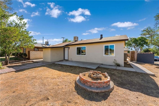 rear view of property featuring central AC unit, a patio area, and an outdoor fire pit