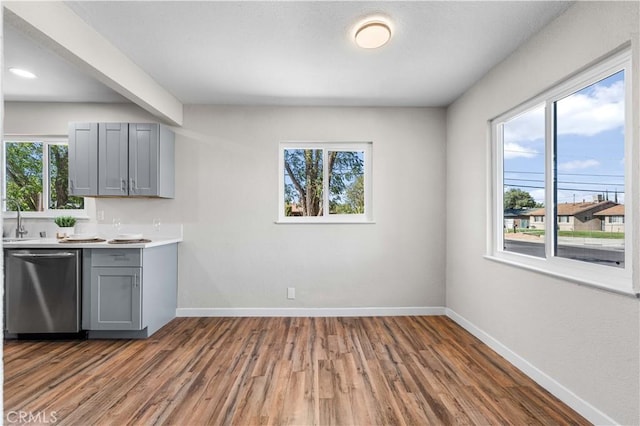 kitchen with stainless steel dishwasher, dark hardwood / wood-style floors, sink, and gray cabinetry