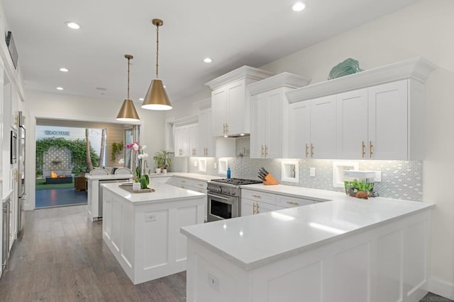 kitchen with white cabinets, kitchen peninsula, high end range, and pendant lighting