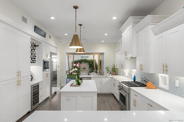 kitchen featuring decorative light fixtures, wine cooler, backsplash, white cabinets, and high quality appliances