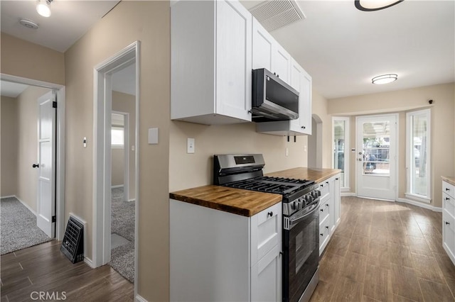 kitchen with dark hardwood / wood-style floors, appliances with stainless steel finishes, white cabinetry, and wooden counters