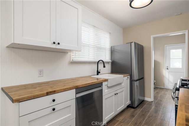 kitchen featuring white cabinets, appliances with stainless steel finishes, wooden counters, dark wood-type flooring, and sink