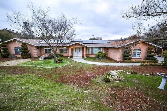 ranch-style house with a front yard and solar panels