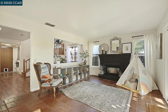 living area with a brick fireplace and dark tile patterned floors