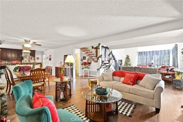 living room featuring ceiling fan, wood-type flooring, and a textured ceiling