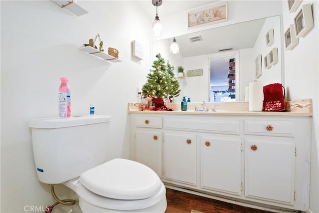 bathroom with toilet, vanity, and hardwood / wood-style flooring